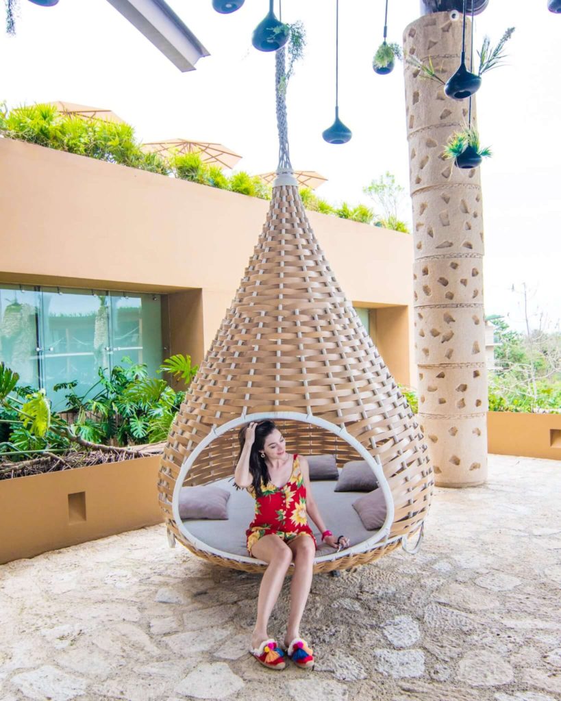 Girl sitting in hanging swing of lobby at Hotel Xcaret Mexico