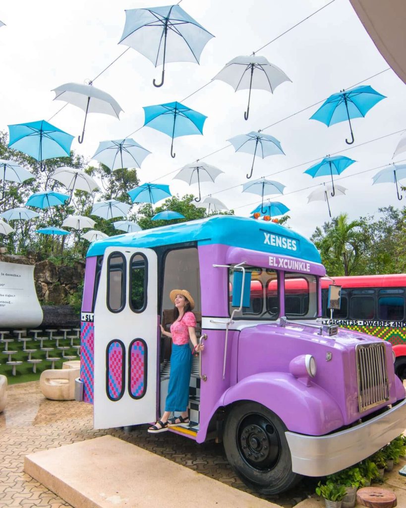 Girl walking out of bus at Xenses Park with umbrellas overhead