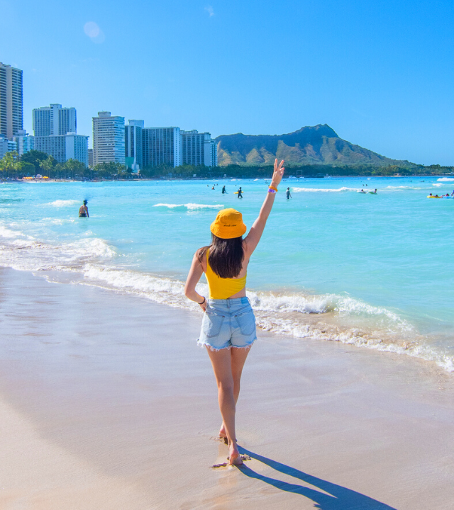 Woman walking along Waiki Beach in Honolulu, Hawaii.