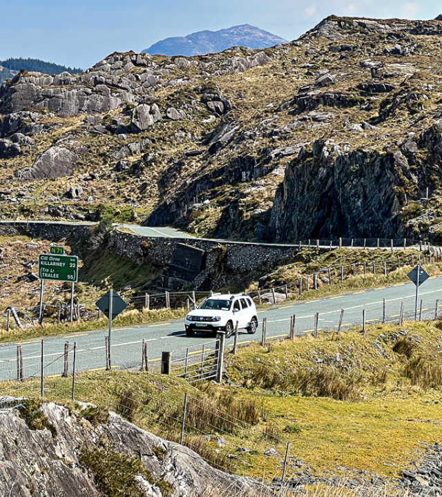 White SUV driving through Molls Gap along the Ring of Kerry in Ireland