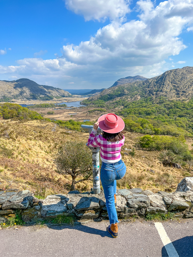 Woman looking out at the view using a tower viewer at Ladies View along the Ring of Kerry in Ireland.