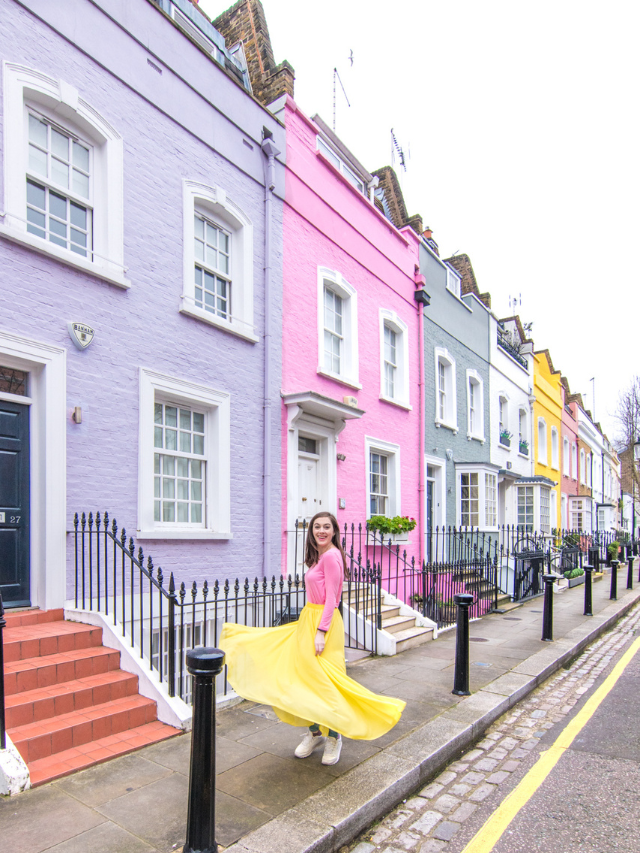 Woman standing in front of colorful houses along Bywater Street in Chelsea in London