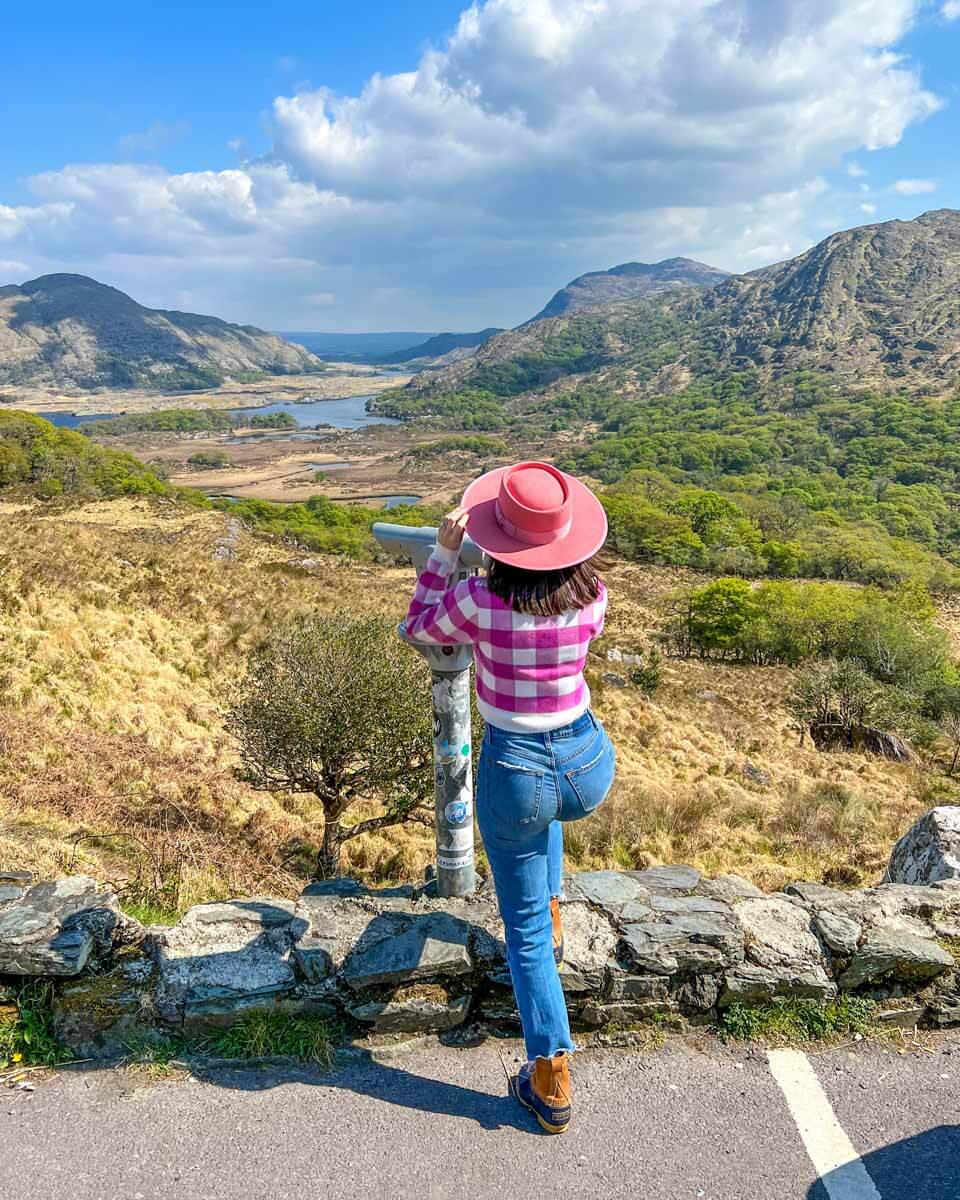 Woman looking through coin-operated binoculars at Ladies View on the Ring of Kerry drive